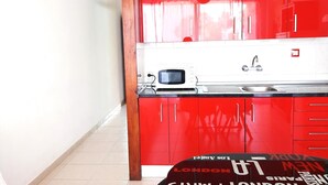 A kitchen with red cabinets, a white countertop, a microwave, and a sink. - Viña del Mar, ocean view (Costa Adeje)