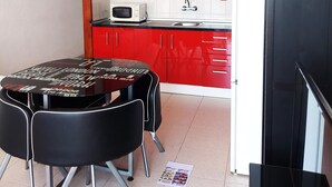 A compact kitchen with red cabinets, a microwave, a sink, and a black table with chairs. - Viña del Mar, ocean view (Costa Adeje)