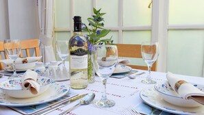 Une table à manger dressée avec des assiettes, des couverts, des verres et une bouteille de vin.