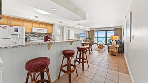 Una cocina moderna con una isla central, taburetes de bar y un comedor con vistas.