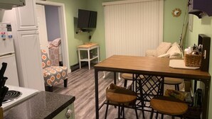 A compact kitchen with a refrigerator, stove, and a small dining table with four stools. - ONE MINUTE WALK to WELLS BEACH, Bellevue by the Sea is your perfect vacation! (Wells)