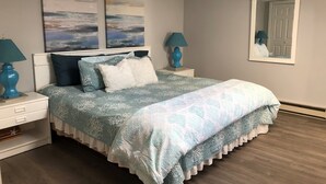 Een slaapkamer met een bed, twee nachtkastjes, een kaptafel en een spiegel.