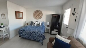 A bedroom with a bed, a desk, a chair, a wardrobe, and a window.