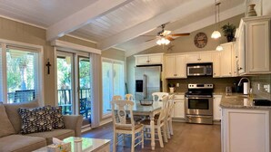A spacious kitchen with white cabinetry, a dining area with a table and chairs, and a ceiling fan.