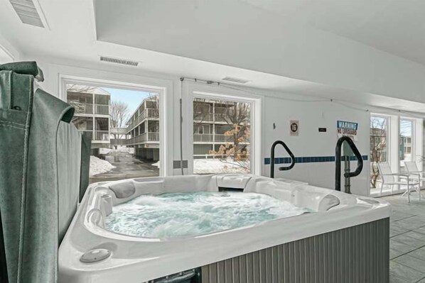 A hot tub in a room with a view of a building outside.