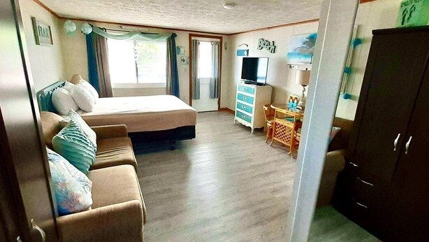 Une chambre à coucher comprenant un lit, un bureau, une armoire et un téléviseur.