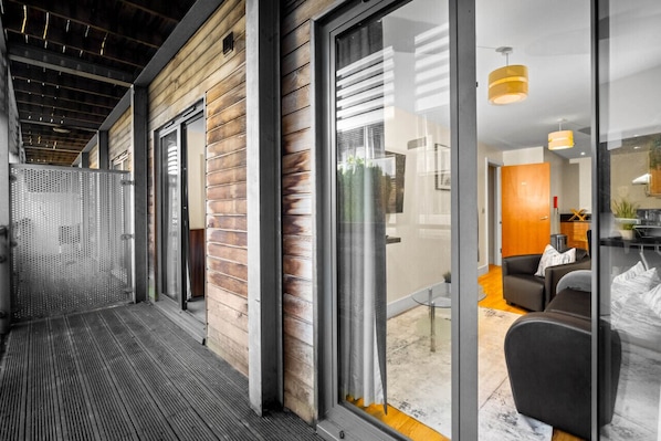 A modern interior with a wooden exterior, large sliding glass doors, and a seating area with a sofa and table.