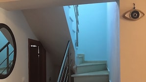 A staircase with a handrail, a door, and a light switch on the wall.