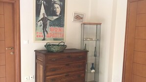 A wooden dresser with drawers and a wicker basket on top, a glass display cabinet with decorative items, and a poster on the wall.