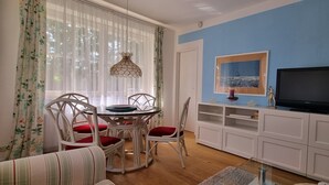 Un coin repas avec une table ronde, des chaises blanches et un luminaire suspendu.