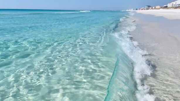 Une plage à l’eau turquoise et limpide, bordée d’un rivage sablonneux.