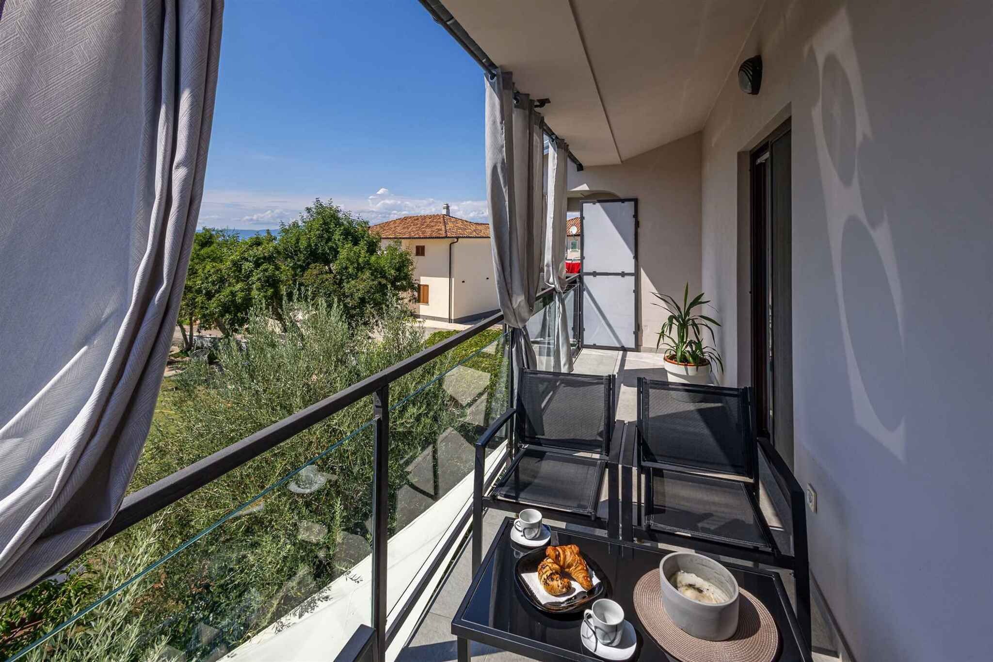A balcony with a glass table, chairs, and a tray with croissants, cups, and a bowl.