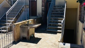 A courtyard with stone flooring, a concrete bench, metal railings, and a staircase leading to an upper level. - Villetta 1P NC La Cinta (San Teodoro)