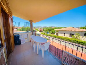 Un balcon avec une table et des chaises, une poubelle et un panneau.
