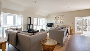 A spacious living room with a fireplace, two sofas, a TV, and a dining area.