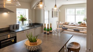 A modern kitchen with a central island, built-in appliances, and pendant lighting.