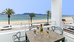 Ein Balkon mit Esstisch, der auf einen Strand mit Palmen und einen klaren Meerblick blickt.