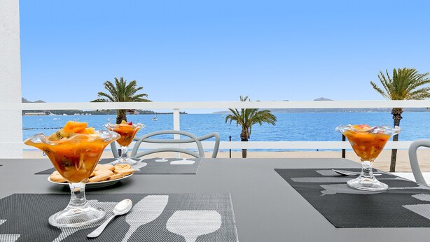 A table set with two cocktails, a plate of cookies, and a view of the sea. - Nice beachfront apartment in Puerto Pollensa (Port de Pollença)