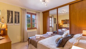 Una habitación de hotel con una cama grande, un armario de madera, un escritorio con lámpara y una ventana con cortinas.