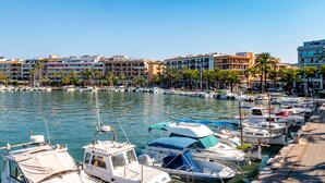 A marina with boats docked, a waterfront promenade, and buildings in the background. - 1st line apartment in Alcudia Beach CAR (Alcúdia)