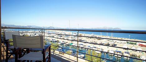 A balcony with a view of a marina and boats, a chair, and a table.