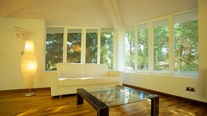Una sala de estar moderna con un sofá blanco, una mesa de centro de vidrio y una lámpara de pie.