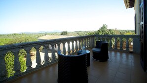 A balcony with a stone balustrade, two black cushioned chairs, and a view of a green landscape with trees and distant hills. - Holiday home 10 minutes from Palma, ideal for large groups (Llucmajor)
