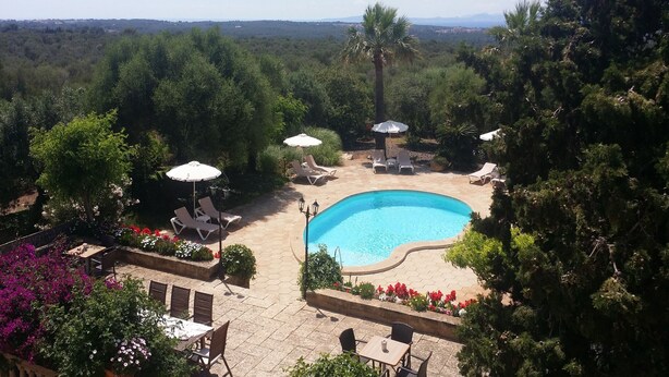 A pool area with lounge chairs and umbrellas, surrounded by lush greenery and trees. - Holiday home 10 minutes from Palma, ideal for large groups (Llucmajor)