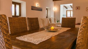 Un comedor con una mesa de madera, sillas tejidas y un candelabro encendido.