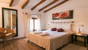 Un dormitorio con una cama grande, una silla, una mesita de noche y un cuadro en la pared.