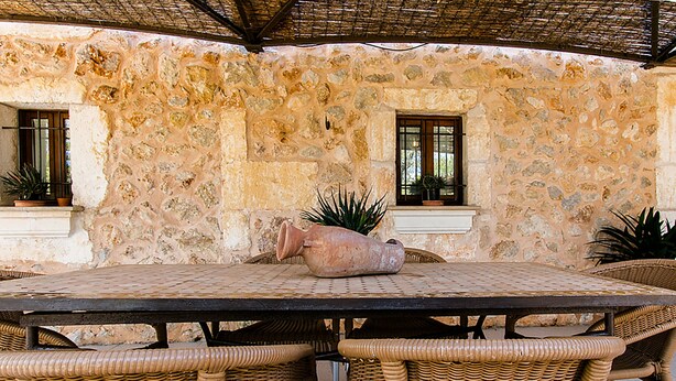 Un muro de piedra con una mesa y sillas de mimbre.