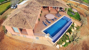 A large house with a swimming pool, outdoor seating, and a view of the surrounding landscape.