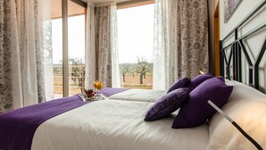 A hotel room with two beds, large windows with curtains, a view of trees, and a breakfast tray on the left bed.