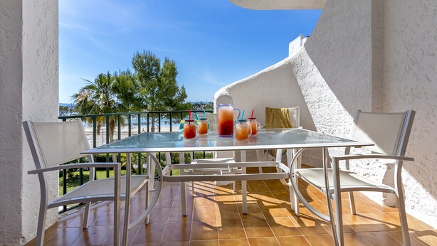 A glass-top table with four drinks, white chairs, and a view of palm trees and the sea. - 1st line apartment Alcudia beach CAB (Puerto de Alcudia)