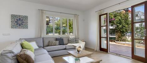 A modern living room with a grey sectional sofa, a white coffee table, and a large sliding glass door leading to an outdoor area.