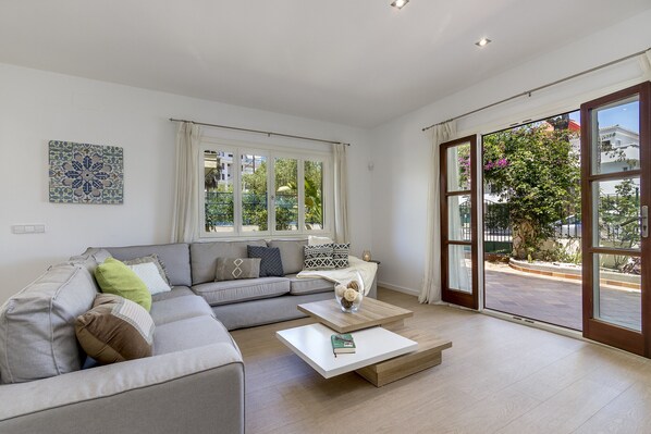 A modern living room with a grey sectional sofa, a white coffee table, and a large sliding glass door leading to an outdoor area.
