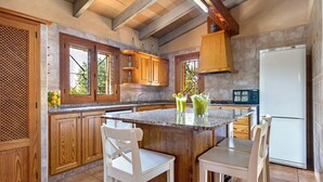 A kitchen with wooden cabinets, a granite countertop, and a white refrigerator. - Country house with amazing swimming pool and garden in a beautiful rural setting (Campanet)