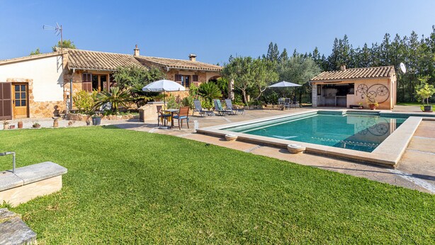 A pool area with a clear blue pool, lounge chairs, and umbrellas. - Country house with amazing swimming pool and garden in a beautiful rural setting (Campanet)