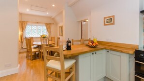 Une cuisine avec un plan de travail en bois, une cuisinière et des placards. On y trouve également un coin repas avec une table et des chaises.