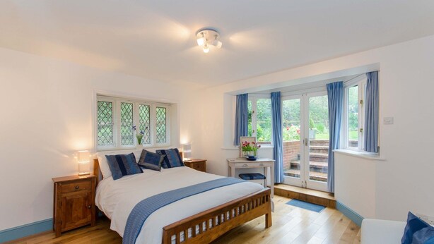 Une chambre à coucher avec un lit en bois, une table de chevet, un bureau avec une chaise et une fenêtre avec des rideaux.