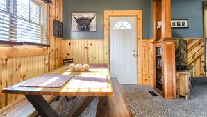 Un comedor con una mesa de madera, bancos y una ventana con persianas.
