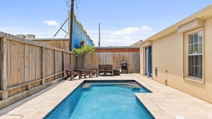 A rectangular swimming pool with a wooden fence and chairs in the background. - 2-min Walk to Beach, Private House with Heated Pool (South Padre Island)
