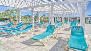 A covered outdoor seating area with blue lounge chairs and umbrellas.