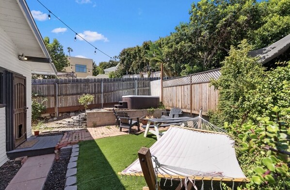 Ein Garten mit Hängematte, Terrassenmöbeln und einem Holzzaun.