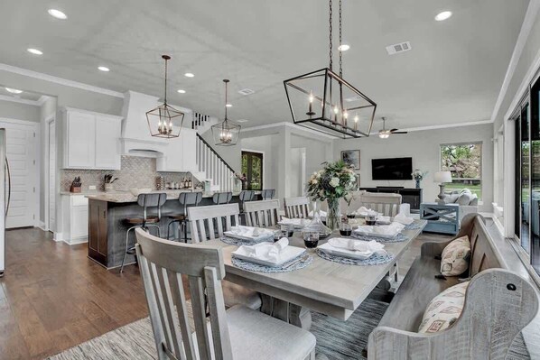 A spacious dining area with a long table set for a meal, surrounded by chairs.