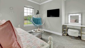Un dormitorio con cama, una mecedora, un escritorio, un televisor y una ventana.