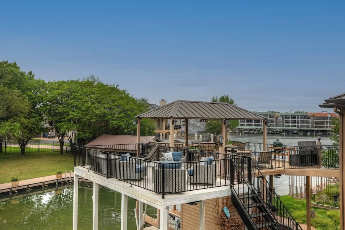 A waterfront deck with outdoor seating and a gazebo, overlooking a body of water.