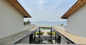 A modern building with a view of the sea and mountains. It features a covered outdoor area with seating and plants. - La Reserva Chapala Resort (Ajijic)