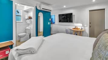 Camera d'albergo con un letto, una scrivania con una sedia, una televisione e un bagno visibile attraverso una porta aperta.