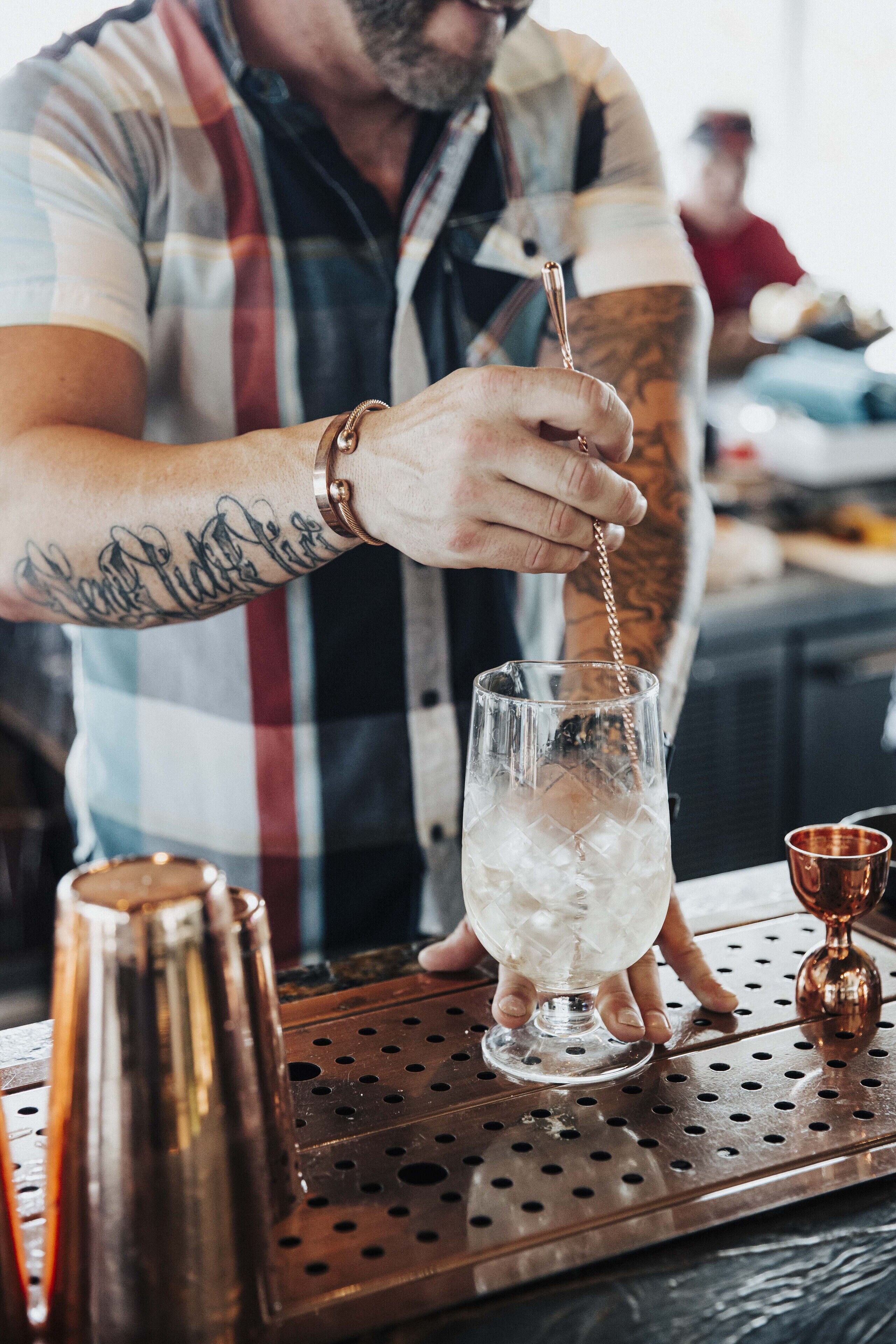 A bartender pouring a drink into a glass.